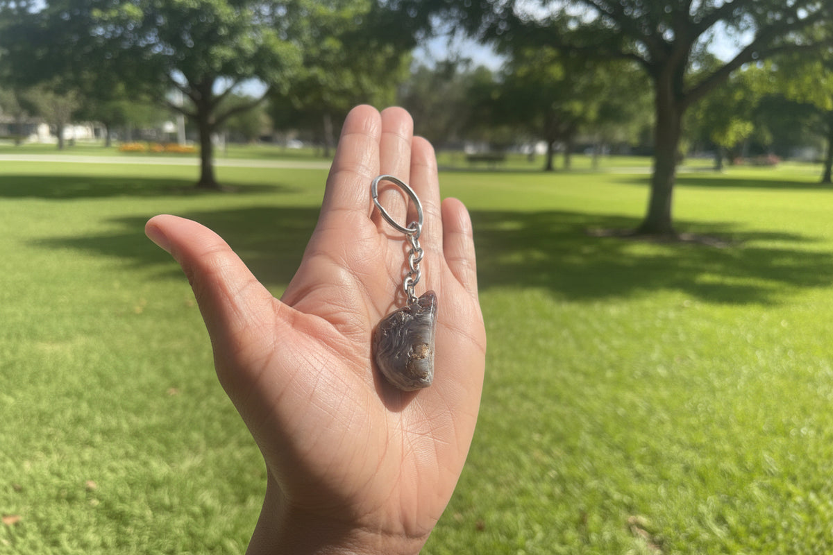 Hand holding a Agate Nodule Mix Keychain with a natural stone pendant outdoors
