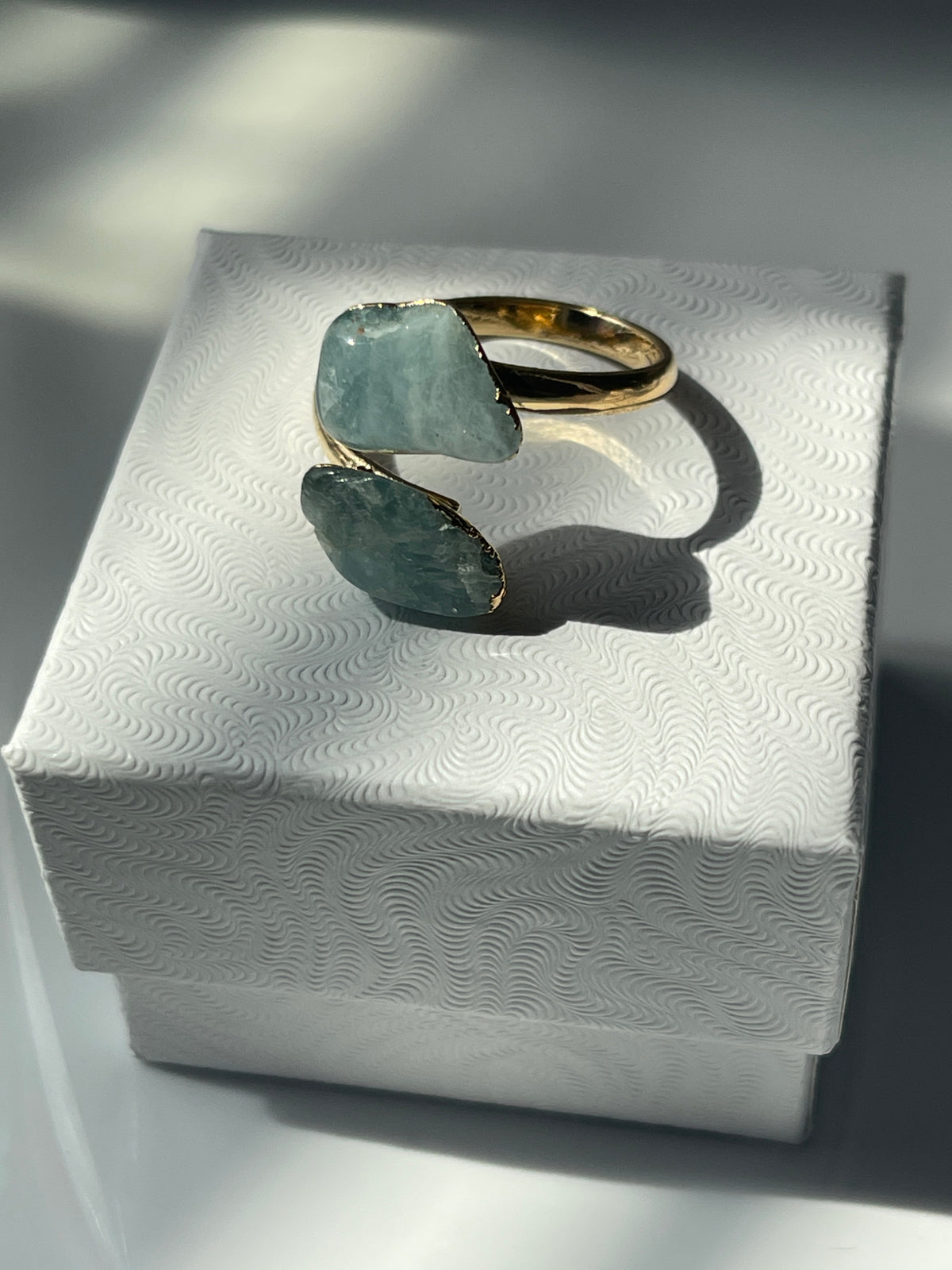 Aquamarine Adjustable Gold Polished Ring sitting on a white luxury jewelry box in Florida