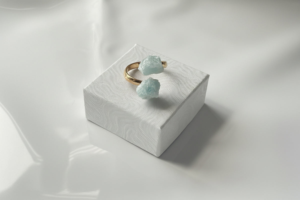 Aquamarine Adjustable Natural Gold Ring siting on a small white jewelry box top
