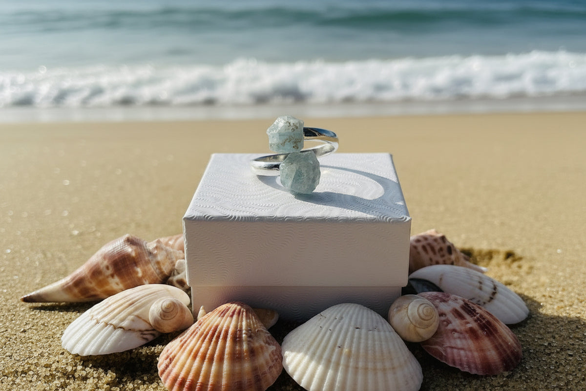 Aquamarine Adjustable Natural Ring Sliver siting on a small white jewelry box on the beach