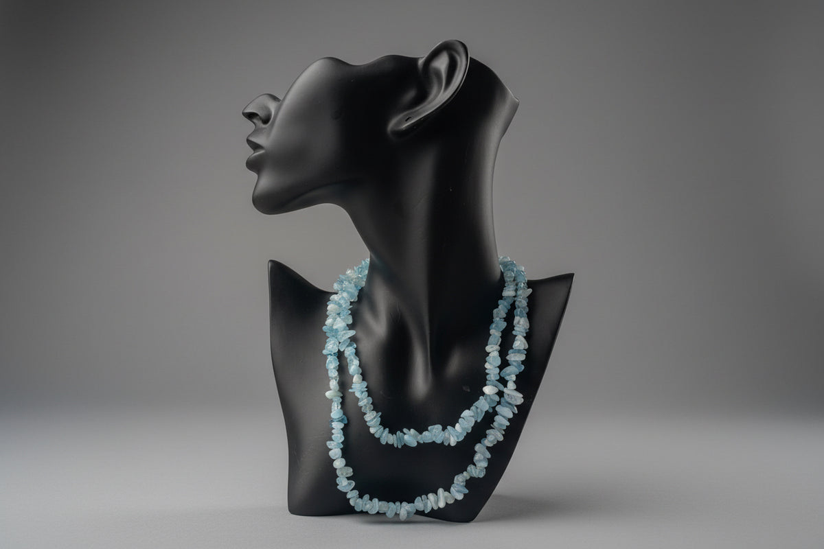 Aquamarine Necklace with blue beads on a black mannequin bust against a blurred gray studio background