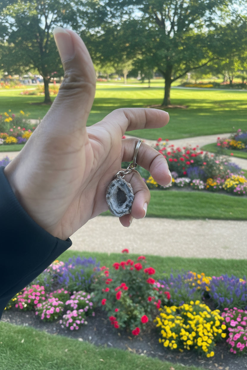 Hand holding a geode crystal pendant with a natural park background