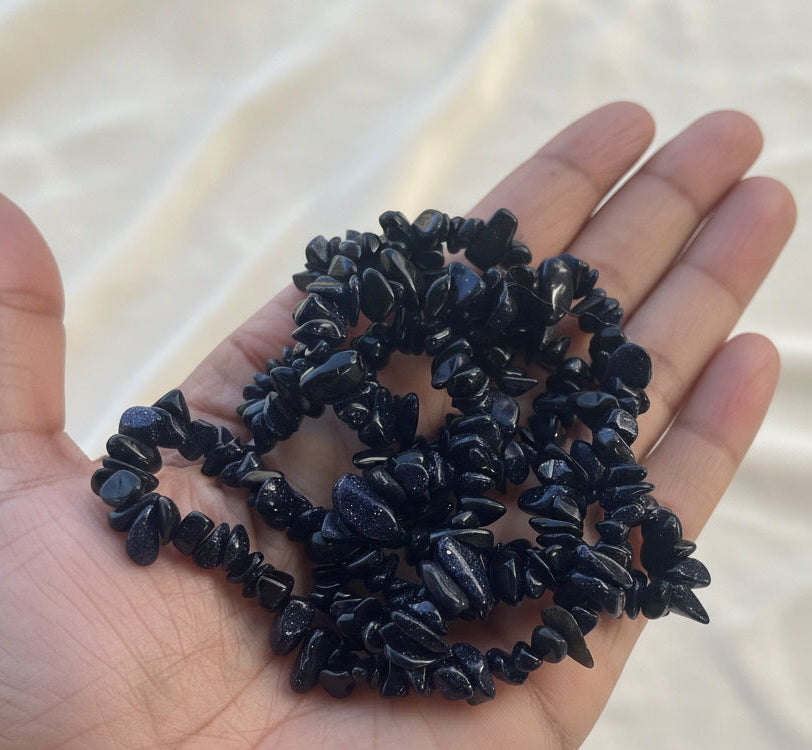 Hand holding a blue beaded necklace against a beige background