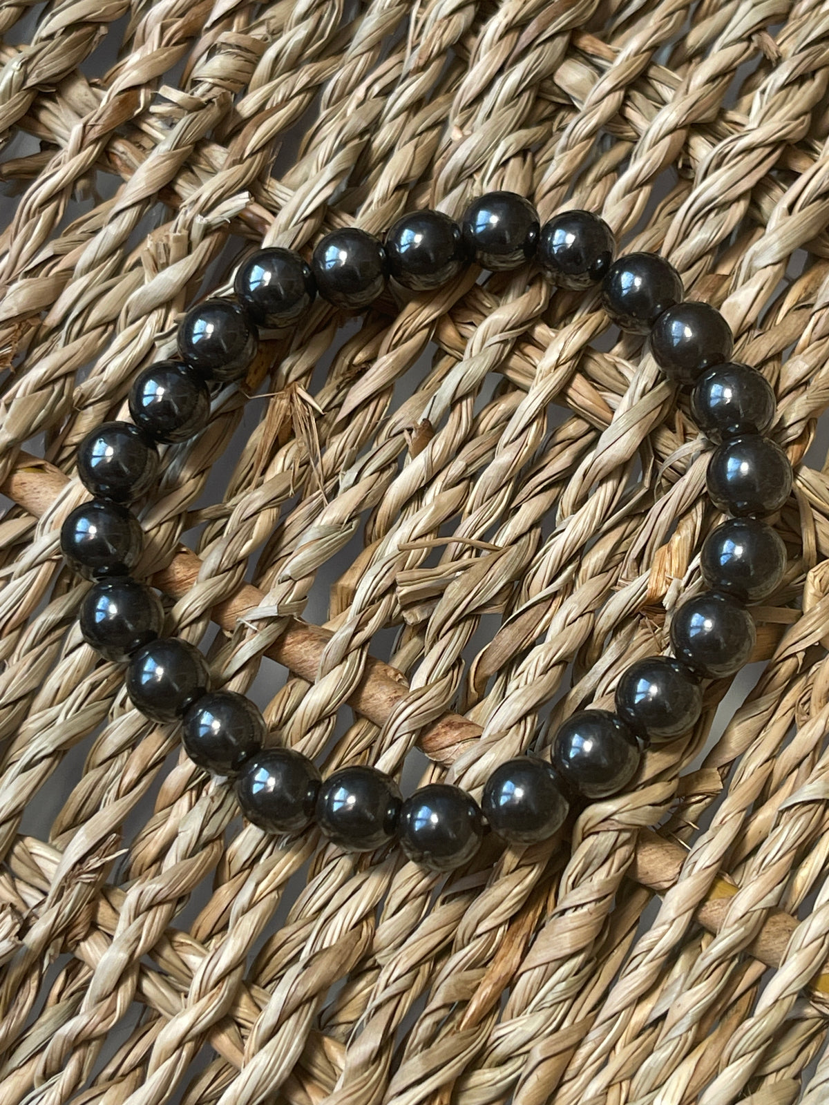 Magnetic Hematite Bracelet Black beaded bracelet on a woven surface