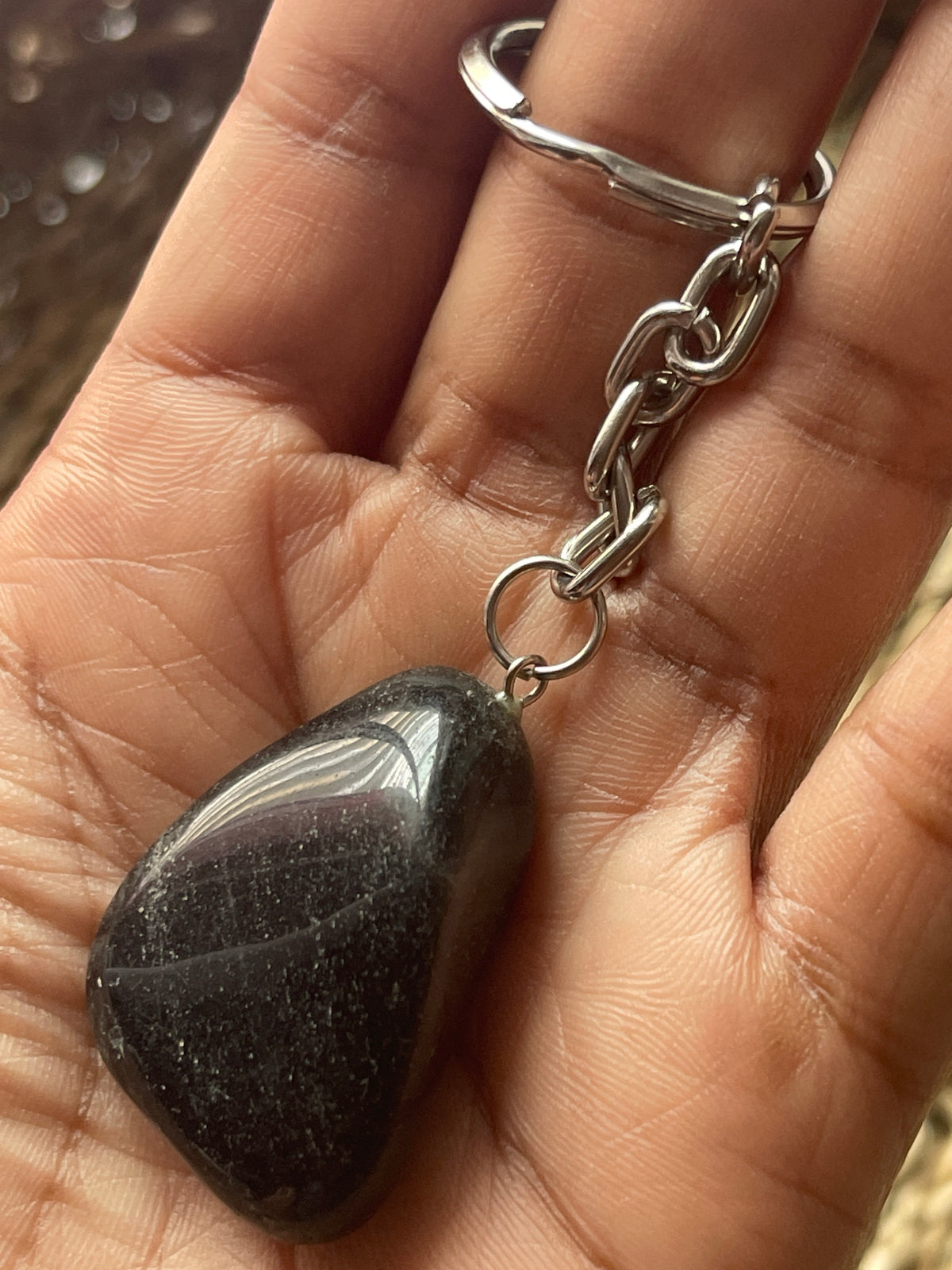 Hand holding a obsidian stone silver keychain with a black stone pendant