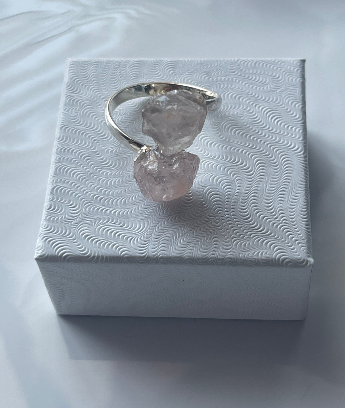 Rose quartz silver plated ring on a textured white jewelry box in Florida