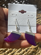 Purple and silver earrings held above a white card with earring hooks.