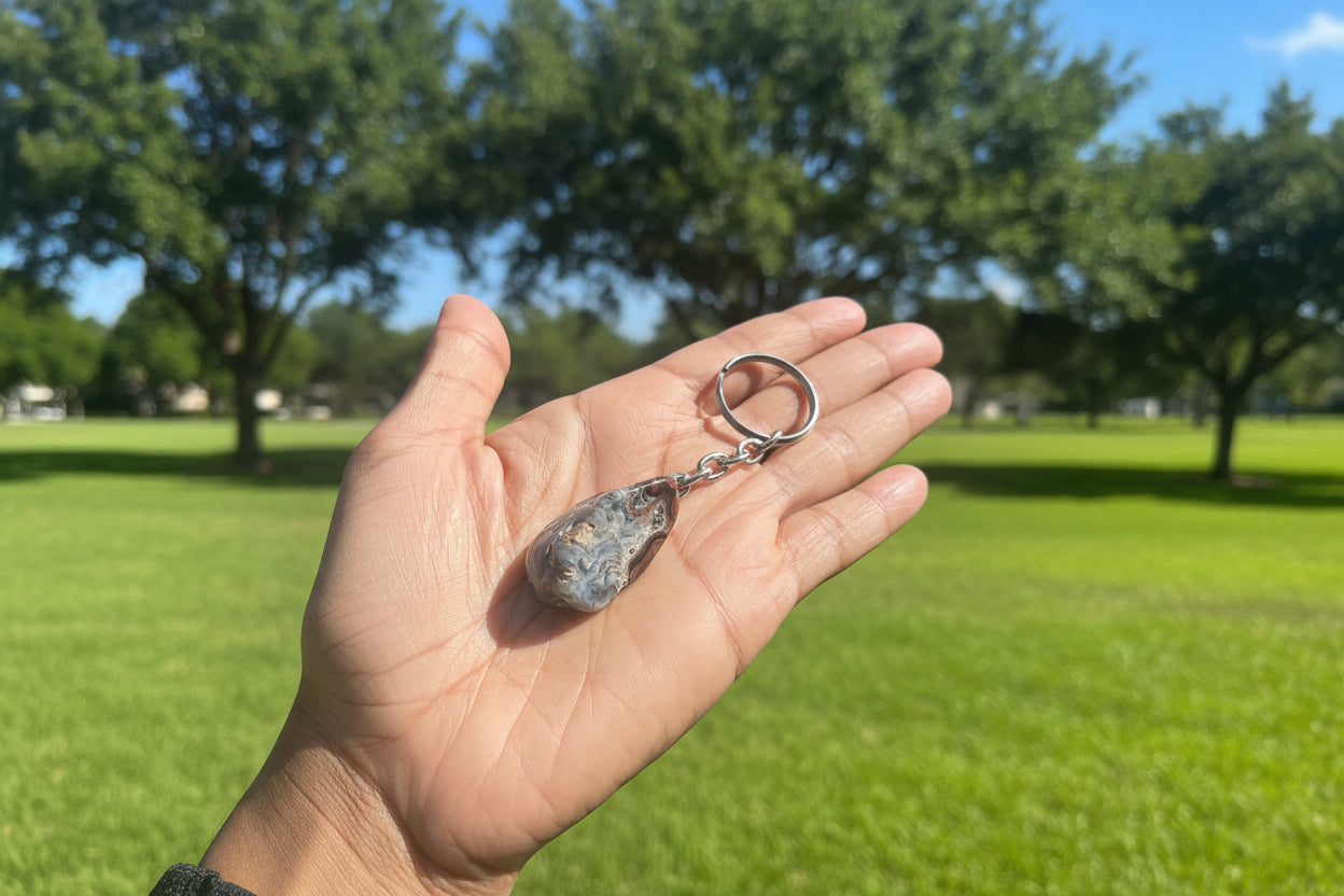 Hand holding a Agate Nodule Mix Keychain with a stone pendant outdoors