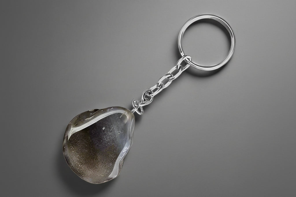 A keychain featuring a polished agate nodule attached to a metal ring and chain, displayed against a gray background.