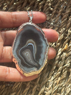 Hand holding a polished agate stone with intricate patterns against a woven background