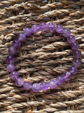 Purple beaded bracelet on a woven surface