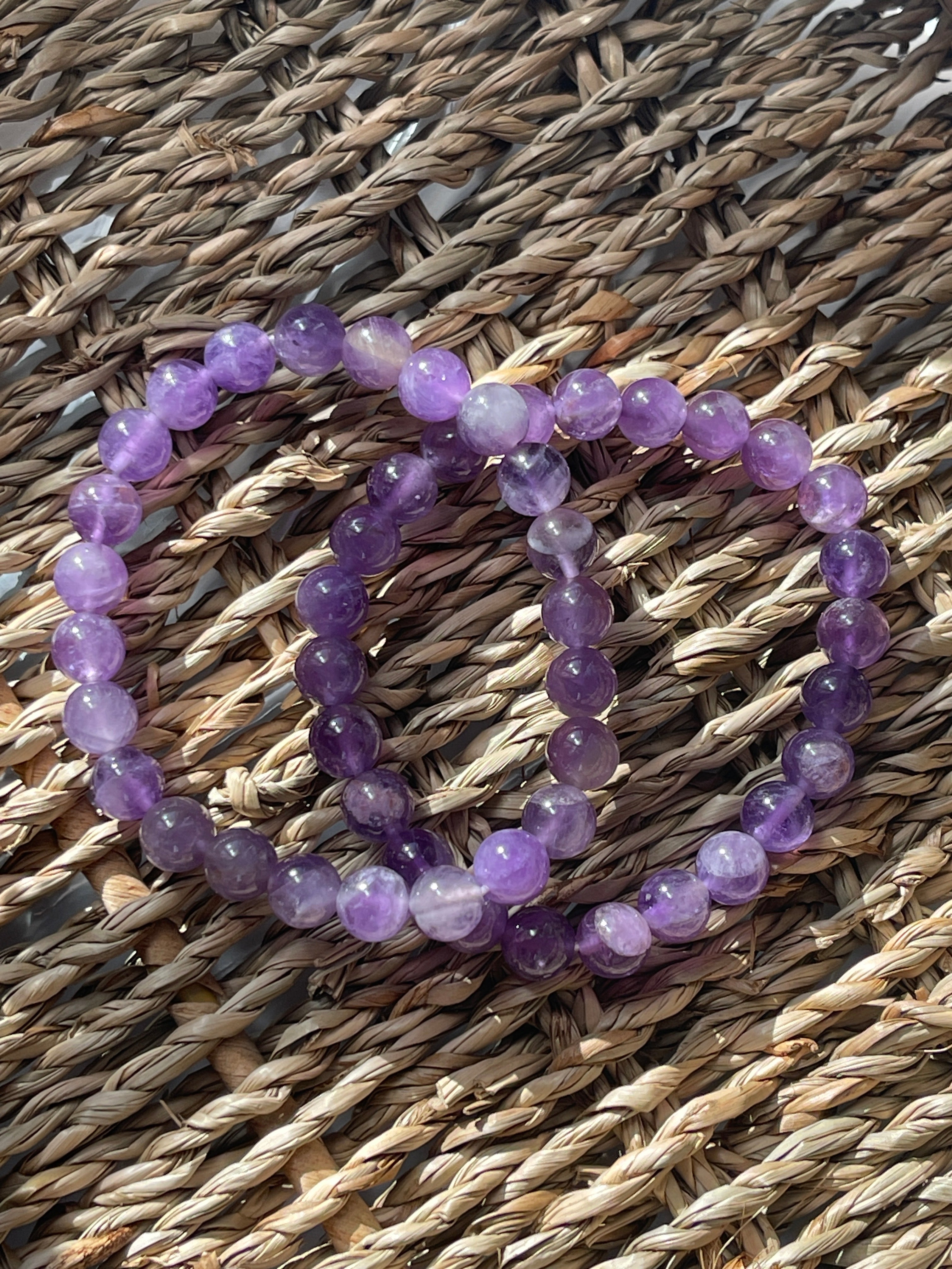Purple beaded bracelets on a woven mat