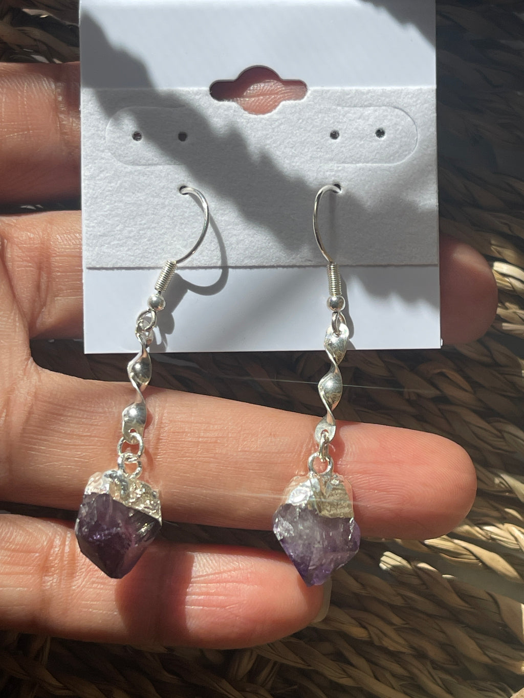 Amethyst Crystal Point Spiral Earrings, Amethyst crystal bracelet on a hand with a branded card in the background