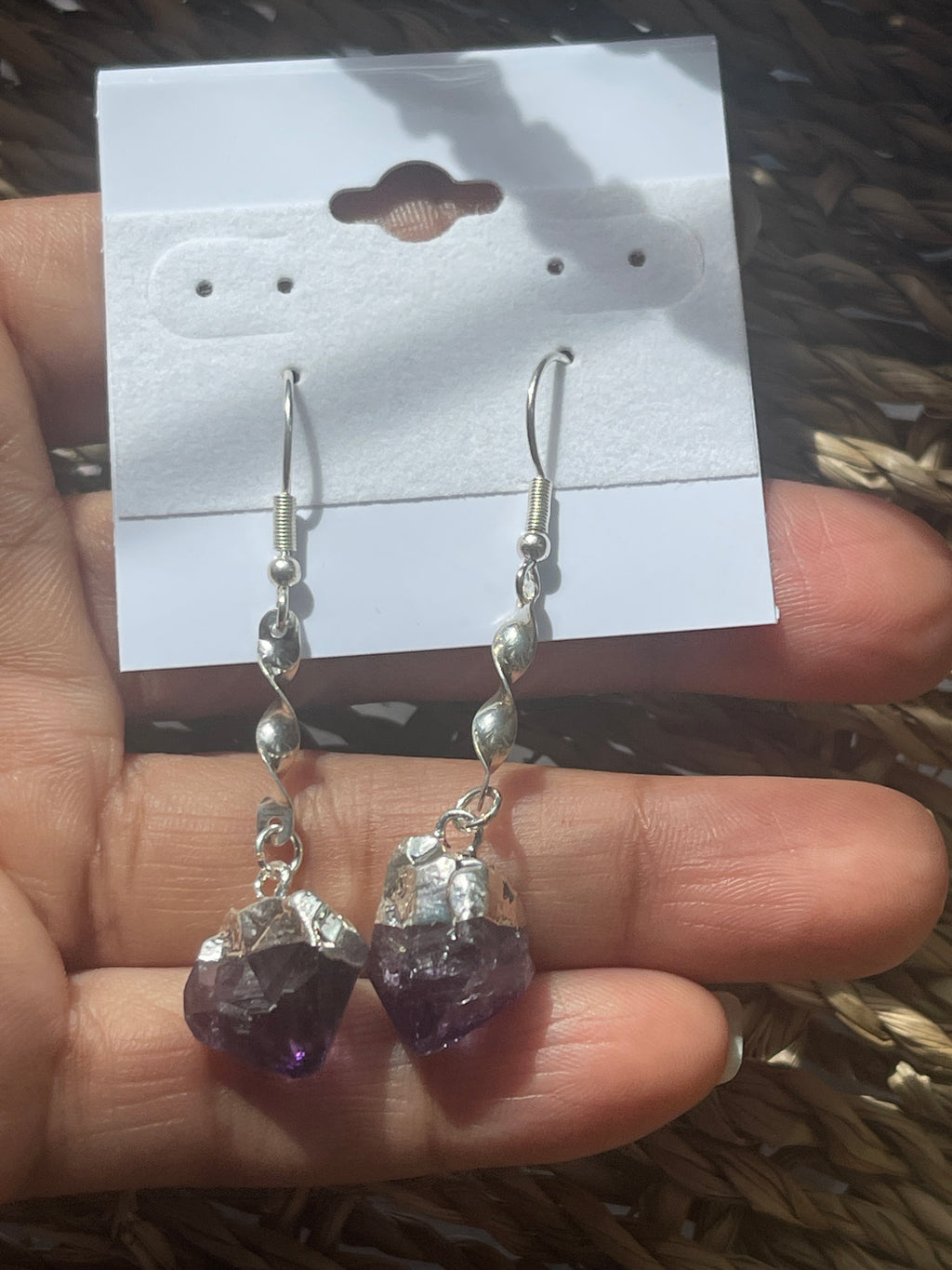Amethyst Crystal Point Spiral Earrings, Amethyst and clear crystal earrings held by a hand with a blurred background