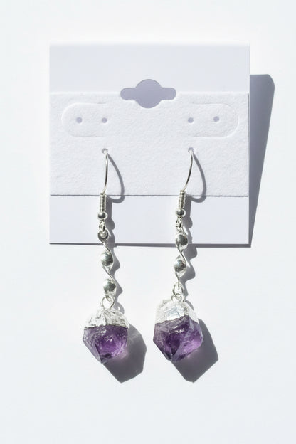 Amethyst Crystal Point Spiral Earrings on a gray card with a textured background