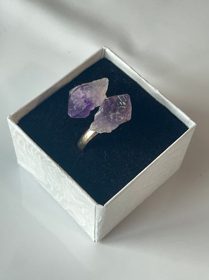 Amethyst crystal ring in a silver box on a white background