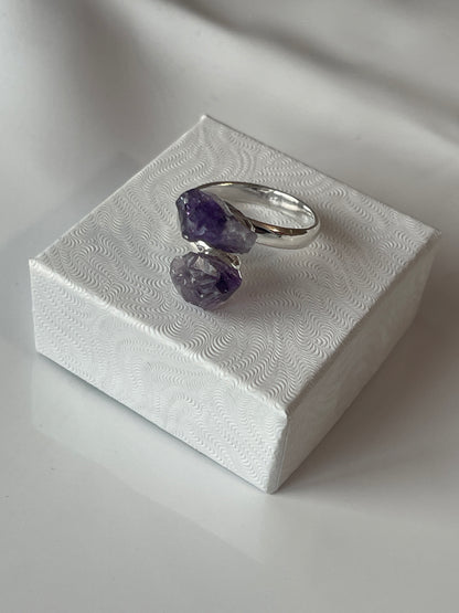 Silver ring with purple gemstones on a textured white surface