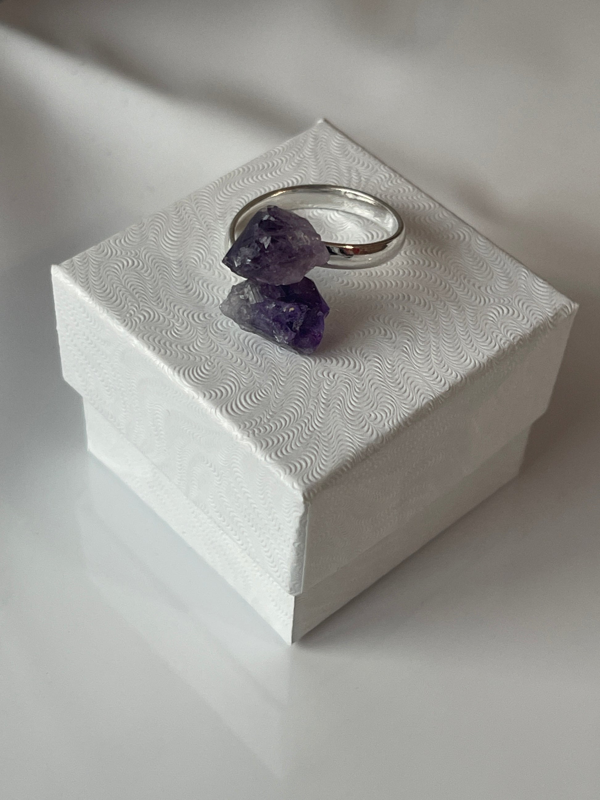 Silver ring with purple stones on a textured white surface