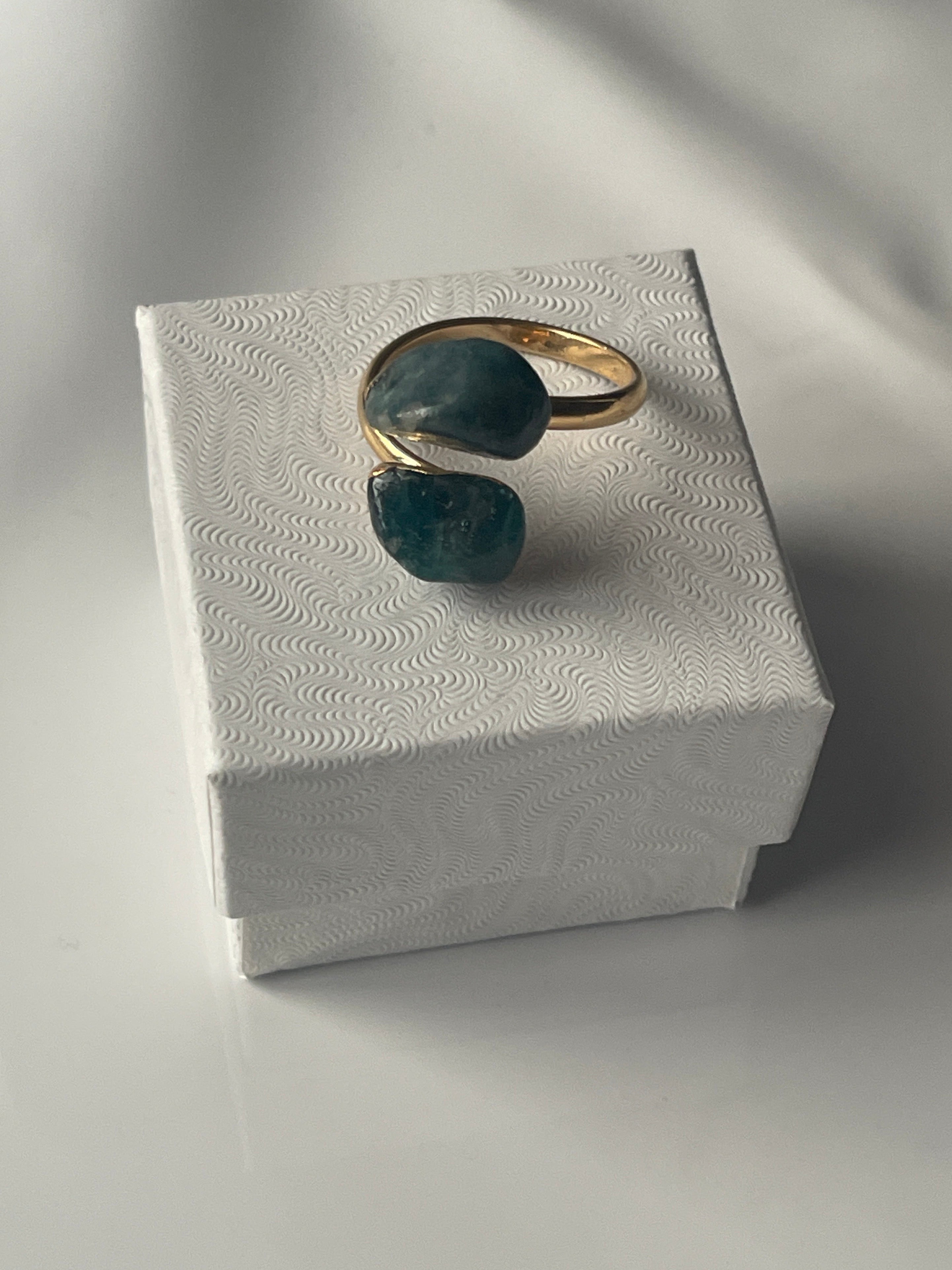 Gold plated Apatite adjustable ring sitting on a small white jewelry box 
