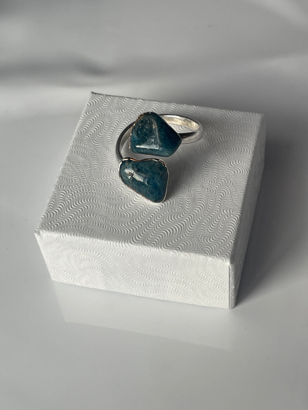Apatite adjustable silver plated ring sitting on a white luxury jewelry box in Florida 
