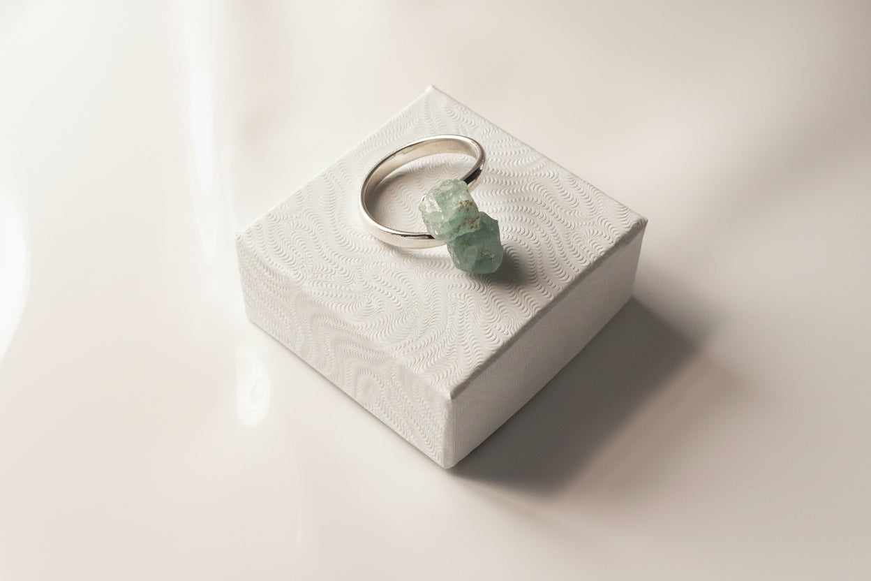 Aquamarine Adjustable Natural Ring Sliver siting inside a small white jewelry box top 