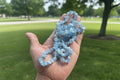 Hand holding a Aquamarine Necklace of blue crystal beads with a blurred park background