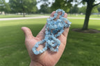 Hand holding a Aquamarine Necklace of blue crystal beads with a blurred park background