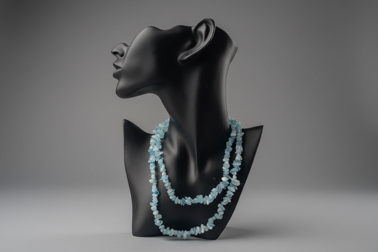 Aquamarine Necklace with blue beads on a black mannequin bust against a blurred gray studio background