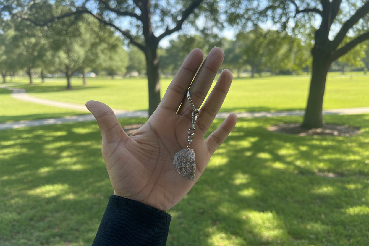 Hand holding a geode keychain with a blurred outdoor background