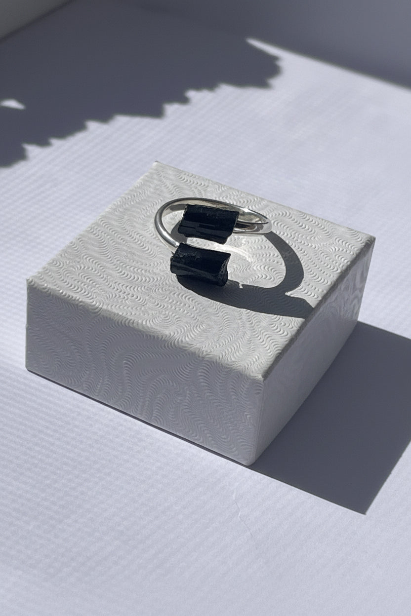 Silver ring with black gemstone on a textured white box. Black Adjustable Silver plated Tourmaline Ring at Pure Energy Crystals 