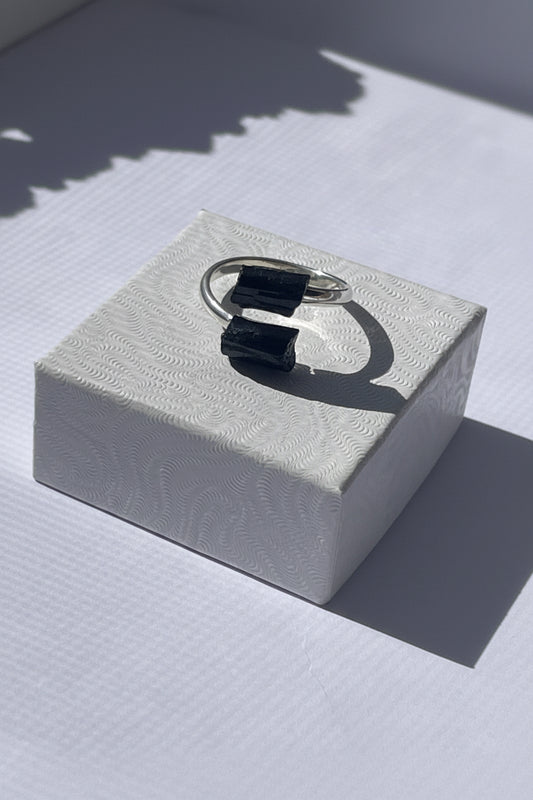 Silver ring with black gemstone on a textured white box. Black Adjustable Silver plated Tourmaline Ring at Pure Energy Crystals 