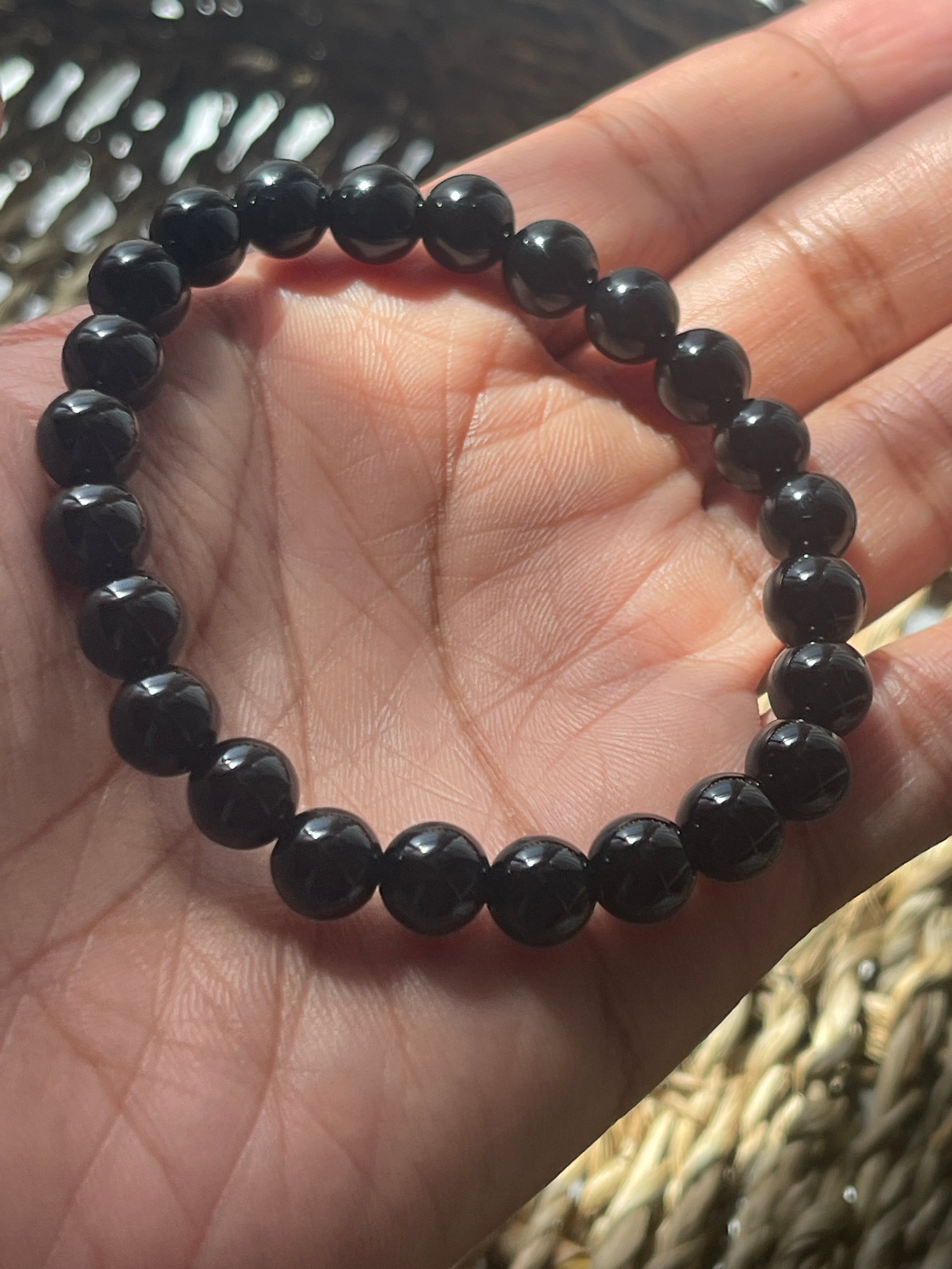 Black beaded bracelet on a hand with a blurred background