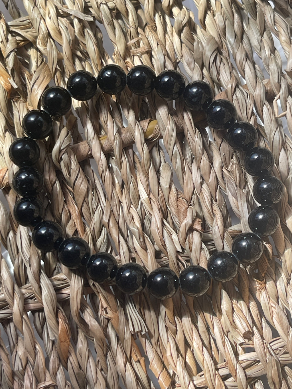 Black beaded bracelet on a woven mat