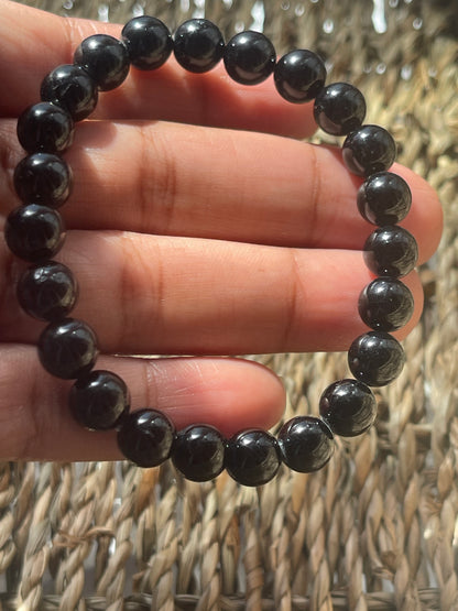 Black beaded bracelet on a hand with a woven background