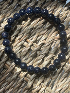 Navy blue beaded bracelet on a woven surface Blue Goldstone 8mm Bracelet at Pure Energy Crystals 