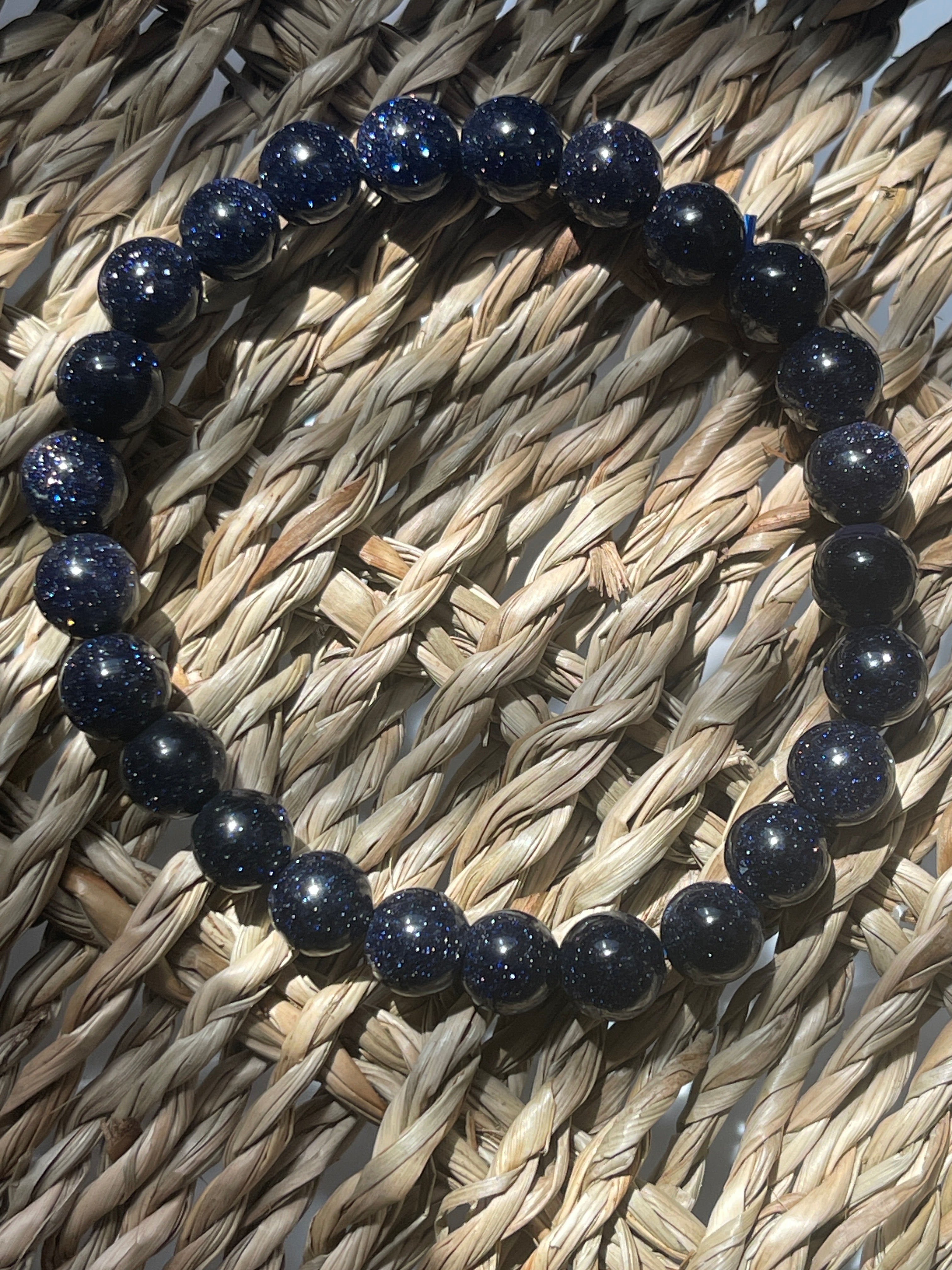 Navy blue beaded bracelet on a woven surface Blue Goldstone 8mm Bracelet at Pure Energy Crystals 