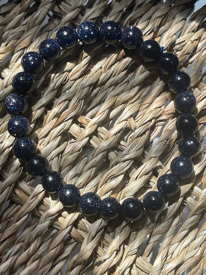 Navy blue beaded bracelet on a woven surface Blue Goldstone 8mm Bracelet at Pure Energy Crystals 