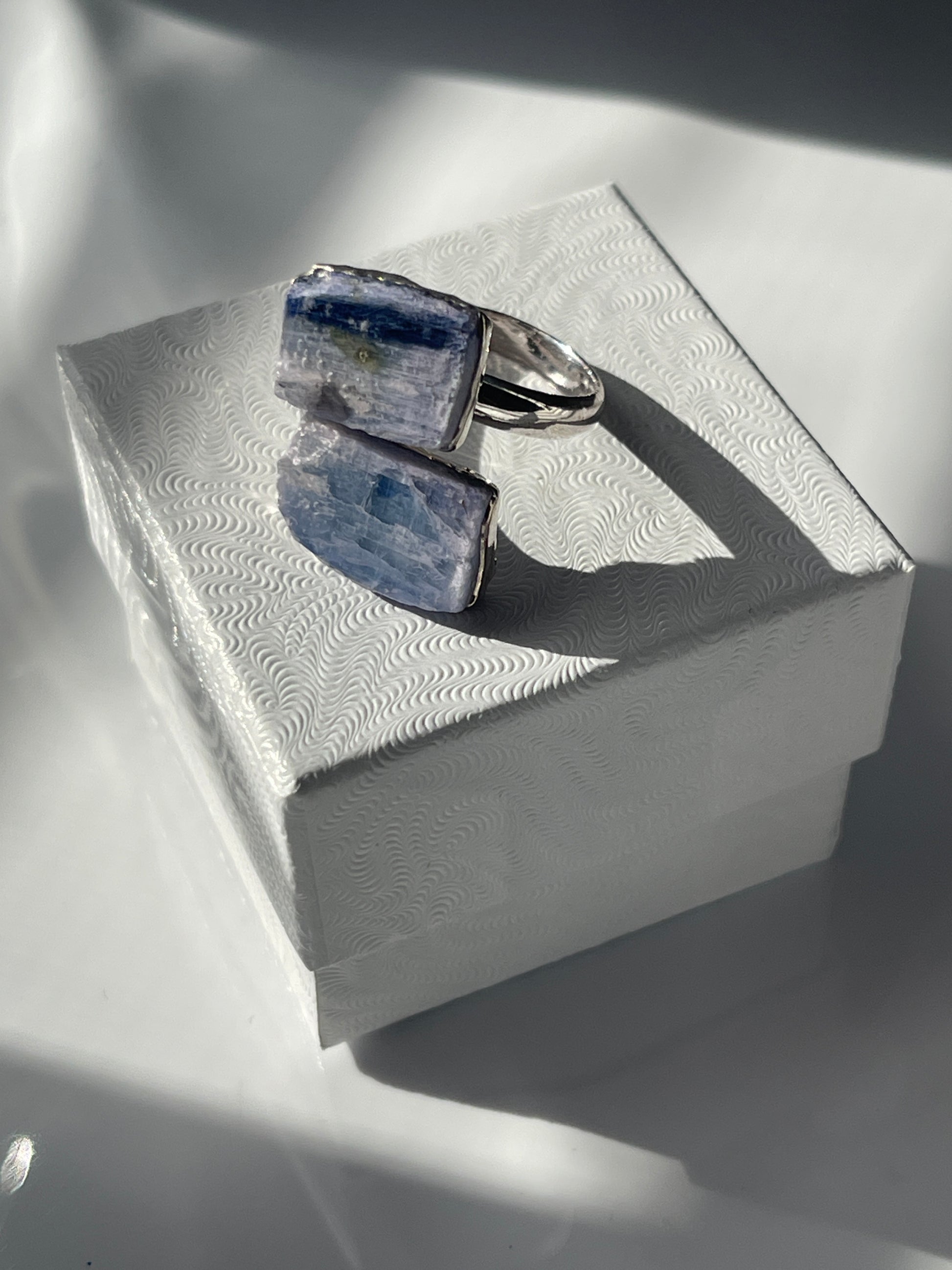 Blue Kyanite silver plated ring sitting on a white jewelry box 