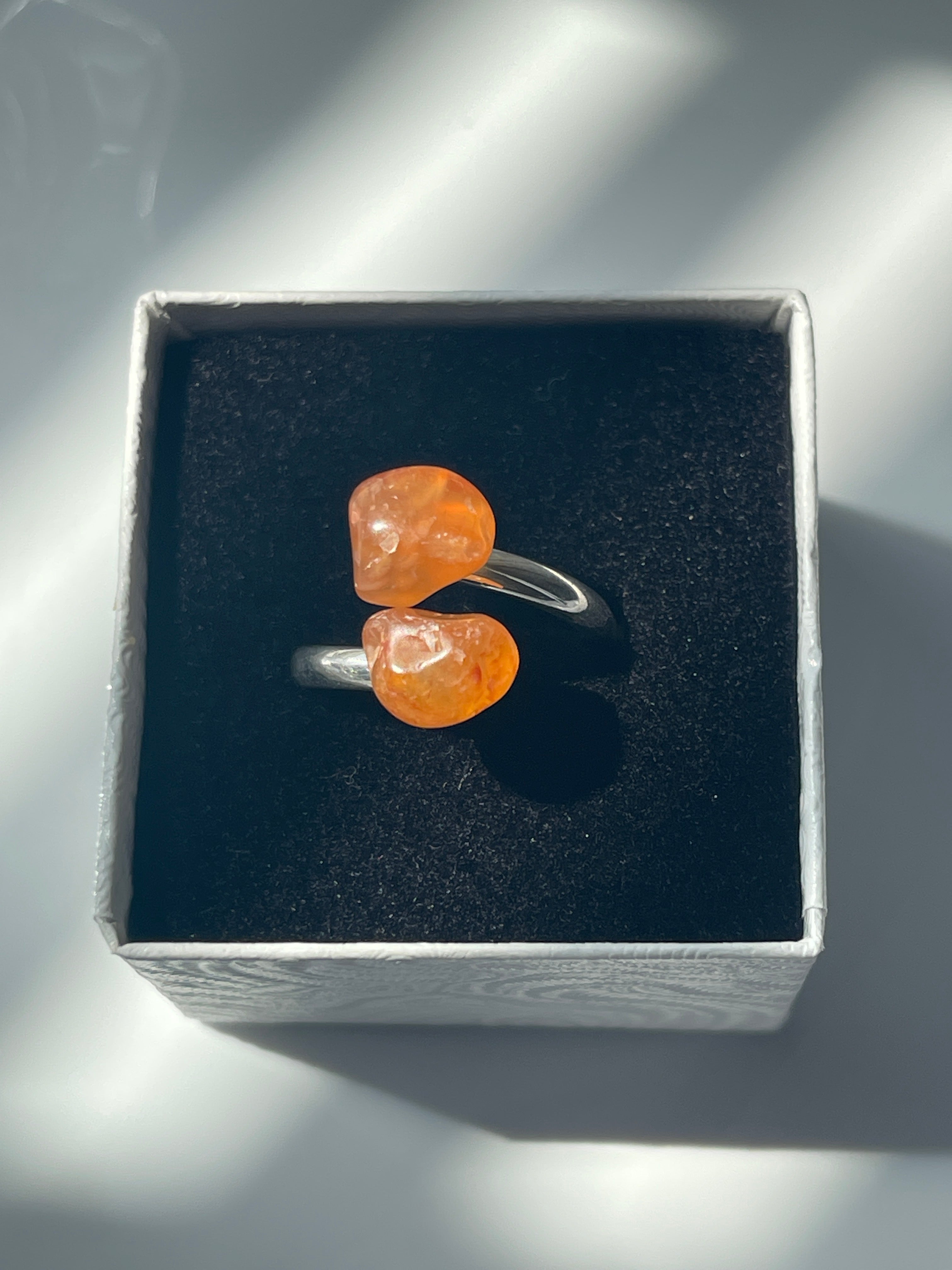 Carnelian Agate silver plated ring with orange stones in a black and white jewelry box on a white background