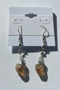 Pair of earrings with citrine stones on a gray background