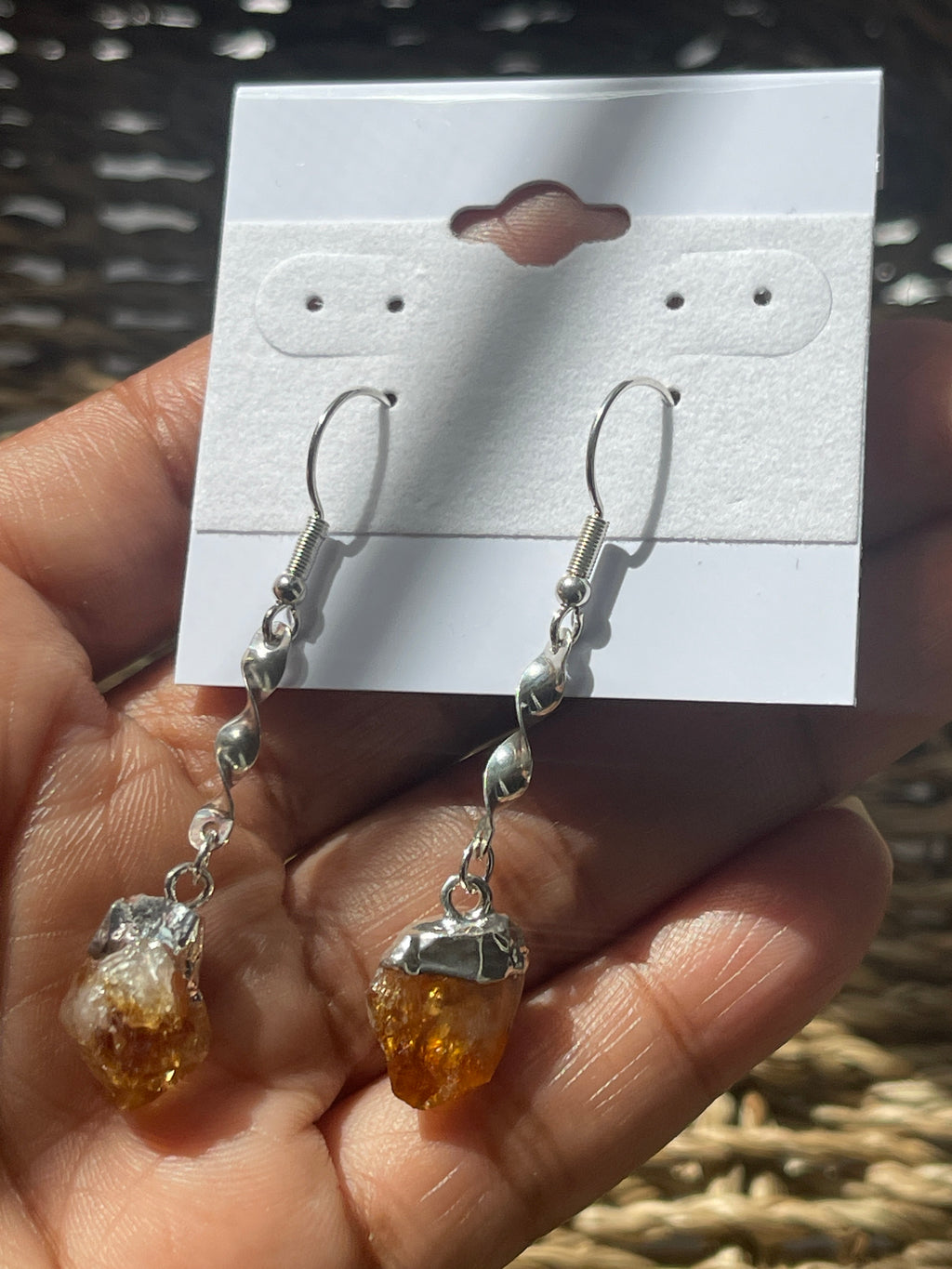 Citrine Crystal Point Spiral Earrings, Hand holding amber and silver earrings with a card displaying earring illustrations.