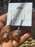 Citrine Crystal Point Spiral Earrings, Hand holding amber and silver earrings with a card displaying earring illustrations.