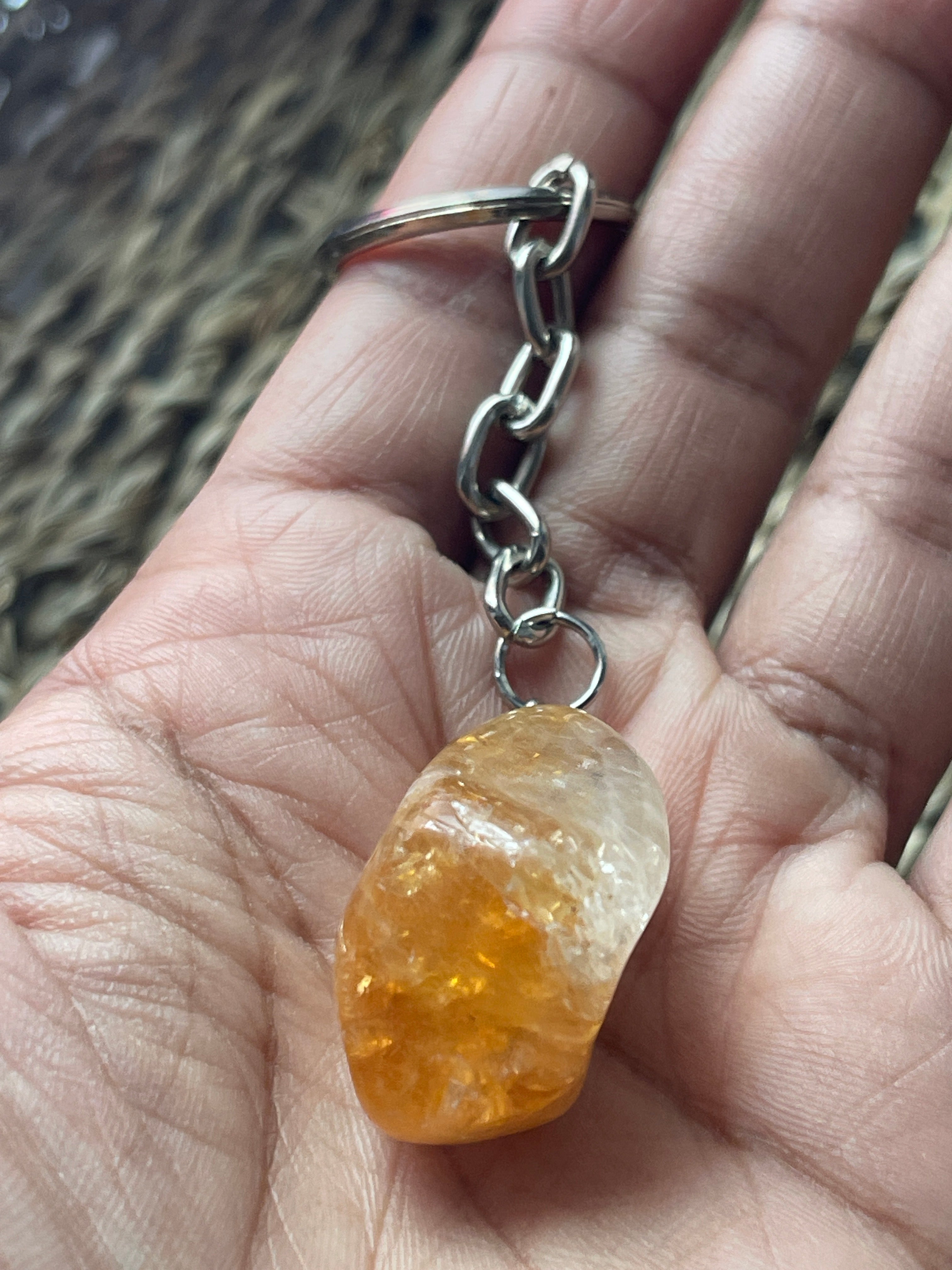 Hand holding a citrine keychain with a large amber-colored stone.