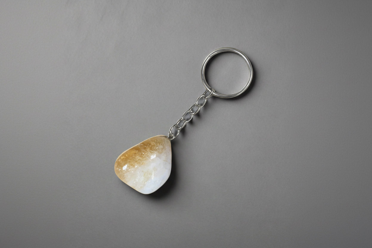 A tumbled Citrine stone keychain attached to a metal ring, set against a gray background.