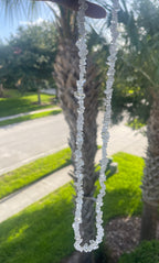 Close-up of a Clear_Quartz_Necklace_30-32_Inches with palm trees and a road in the background