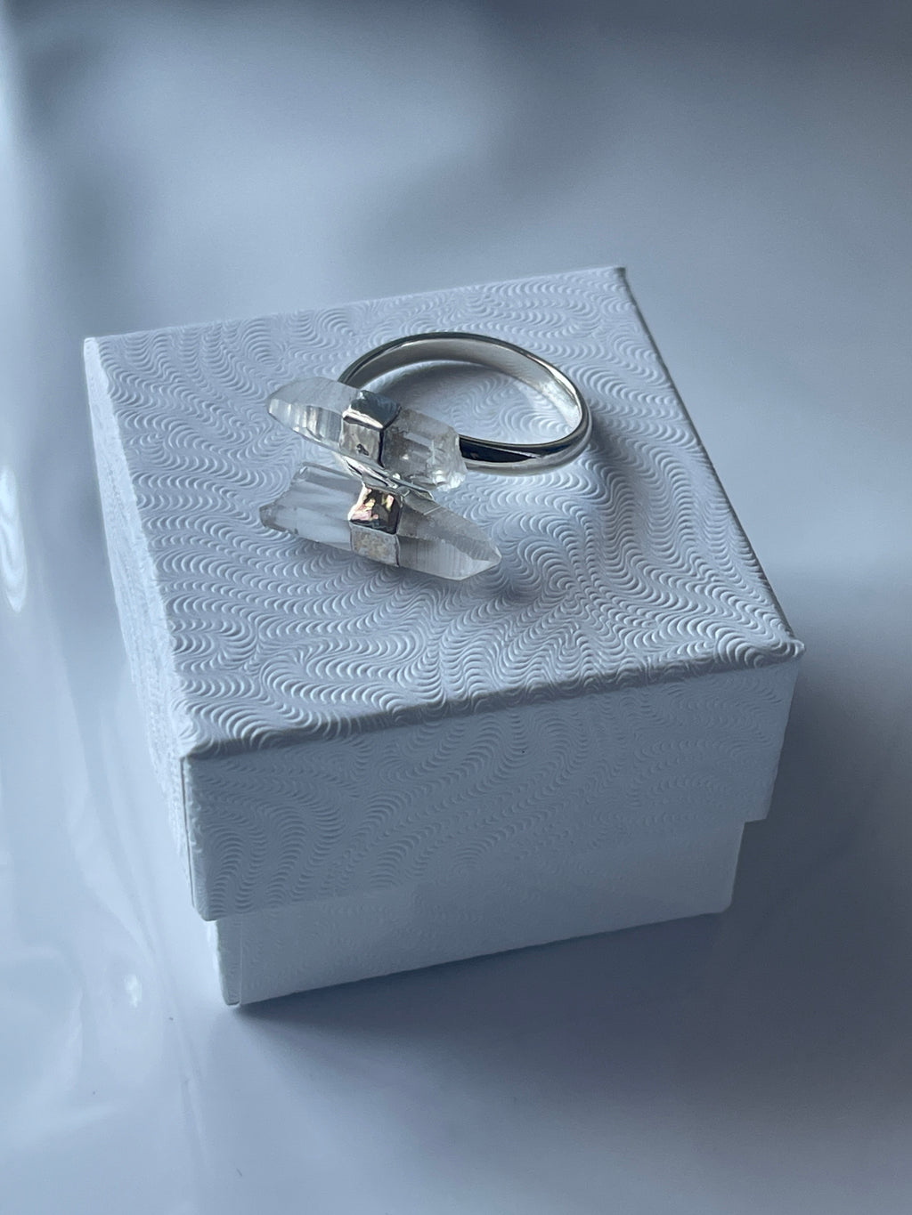Silver Clear Quartz ring with a clear gemstone in a textured white jewelry box on a matching white background