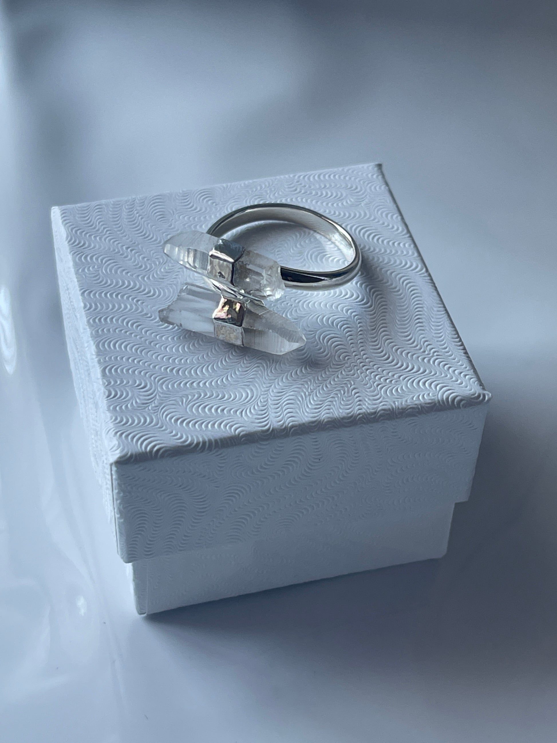 Silver Clear Quartz ring with a clear gemstone in a textured white jewelry box on a matching white background