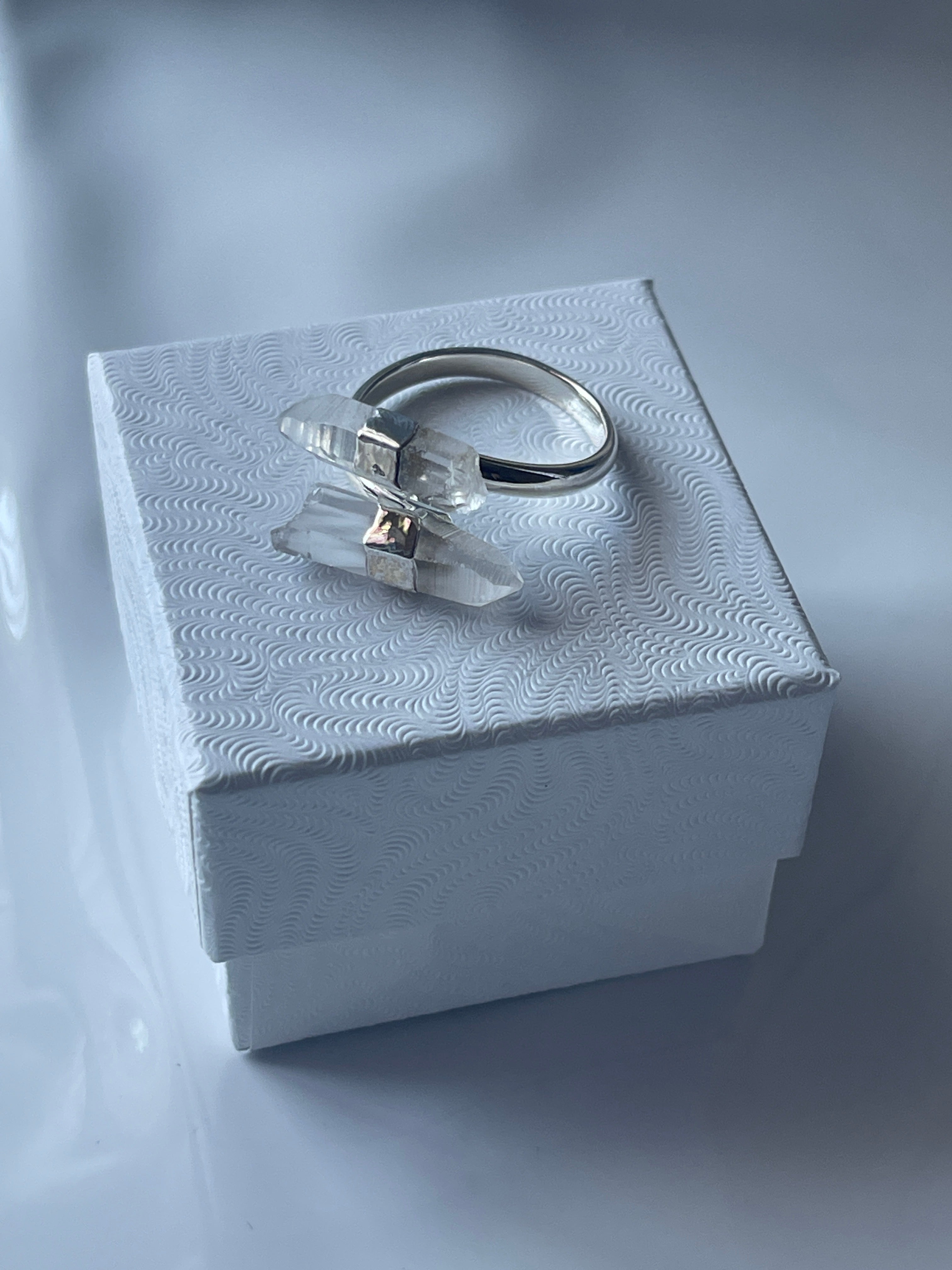Silver Clear Quartz ring with a clear gemstone in a textured white jewelry box on a matching white background