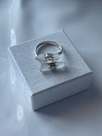 Silver clear quartz ring with a clear stone on a textured white box against a white  background