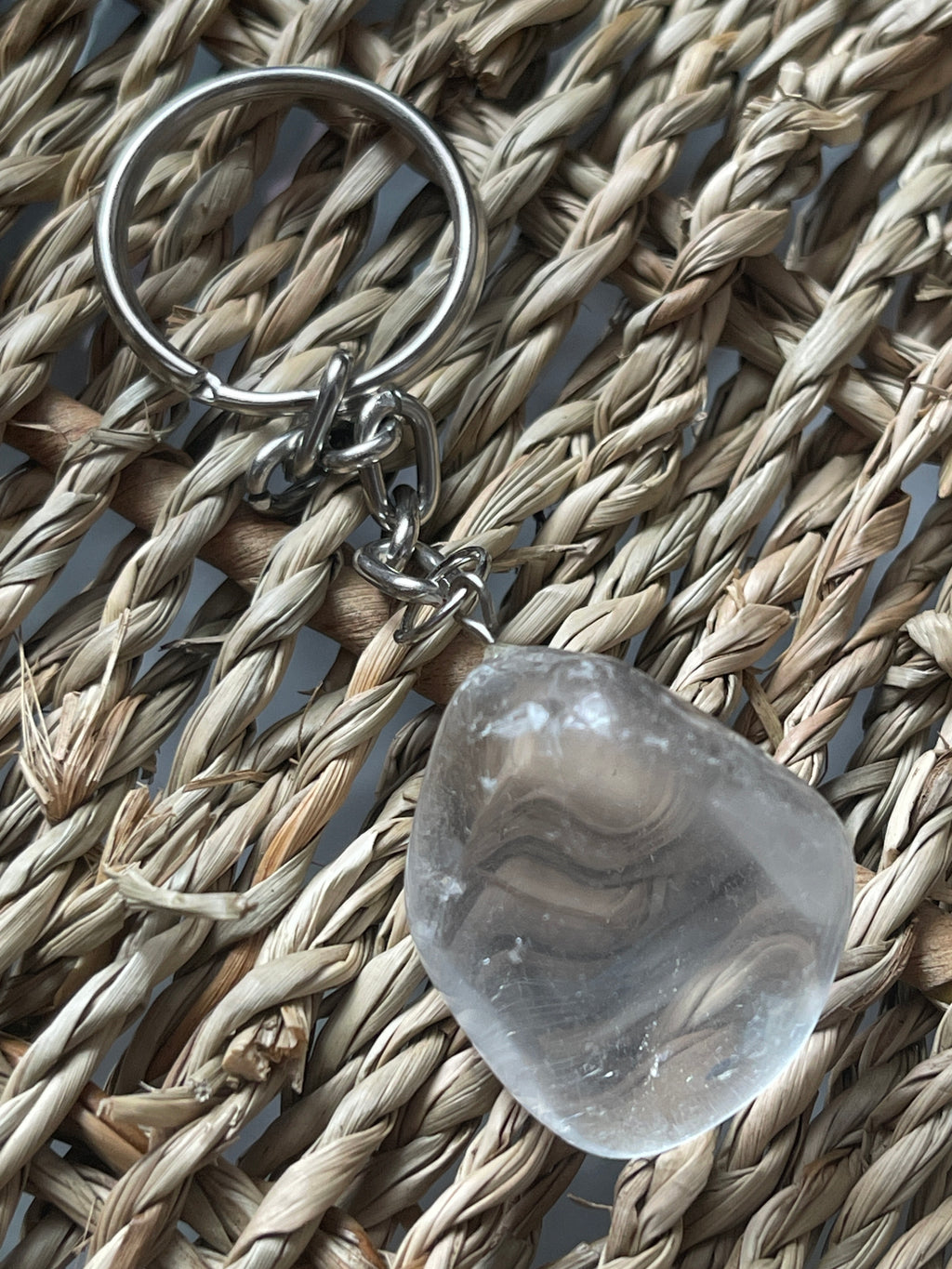 Clear stone with a keychain on a woven surface